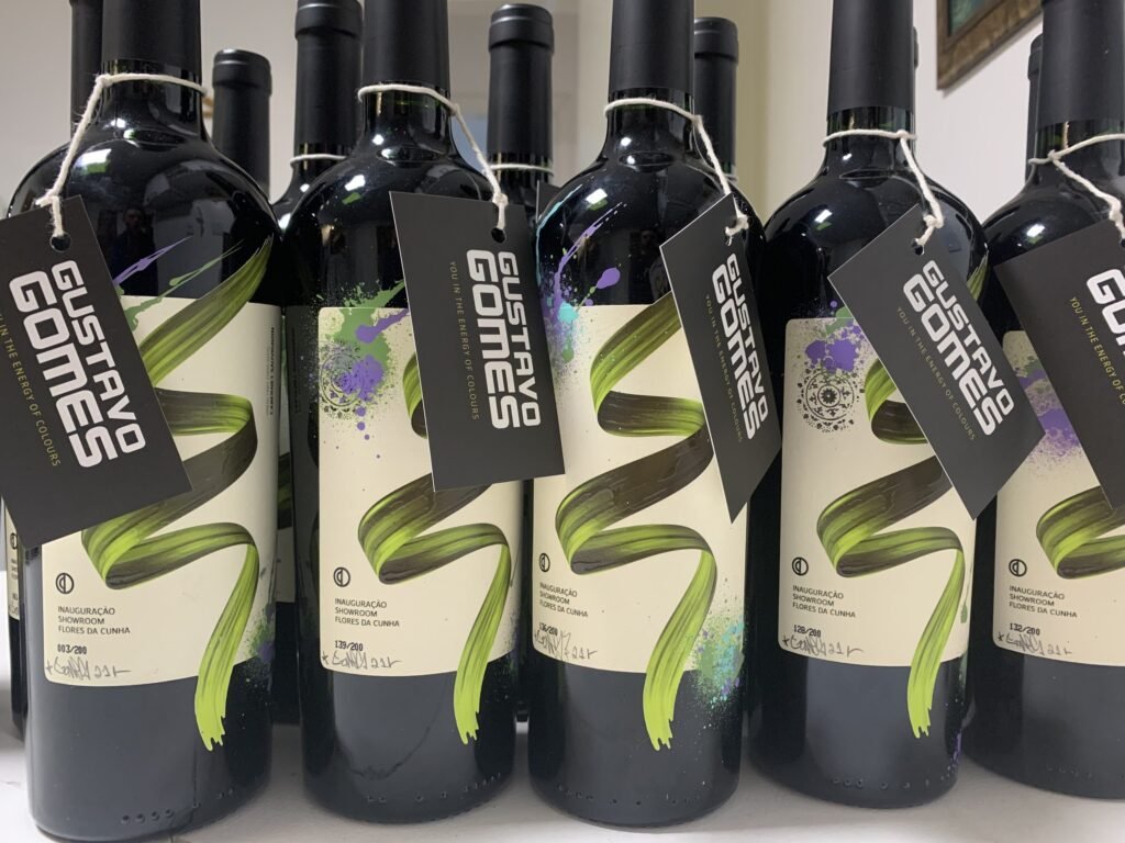 Fileira de garrafas de vinho com rótulo pintado à mão e etiqueta Gustavo Gomes