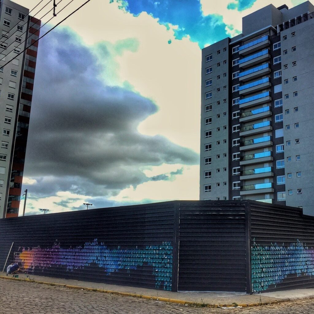 A esquina do tapume pintado, com os prédios e o céu ao fundo