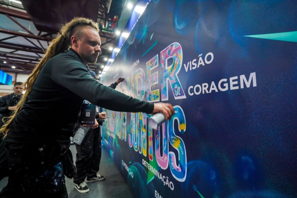 Gustavo Gomes pintando com spray as letras sobre o fundo azul