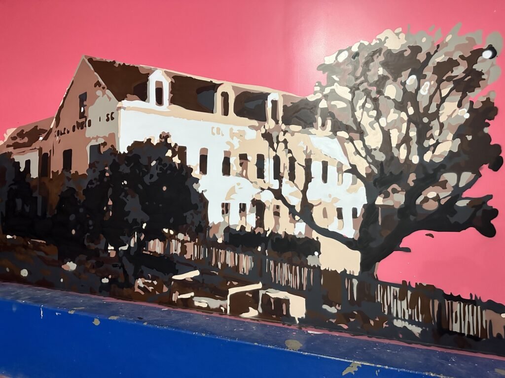 Detalhe do prédio histórico do colégio pintado sobre fundo rosa