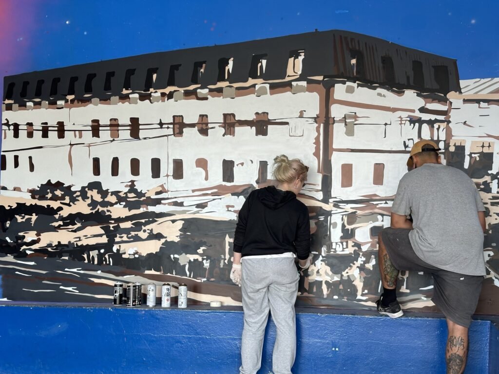 Duas pessoas pintando o prédio histórico na parede