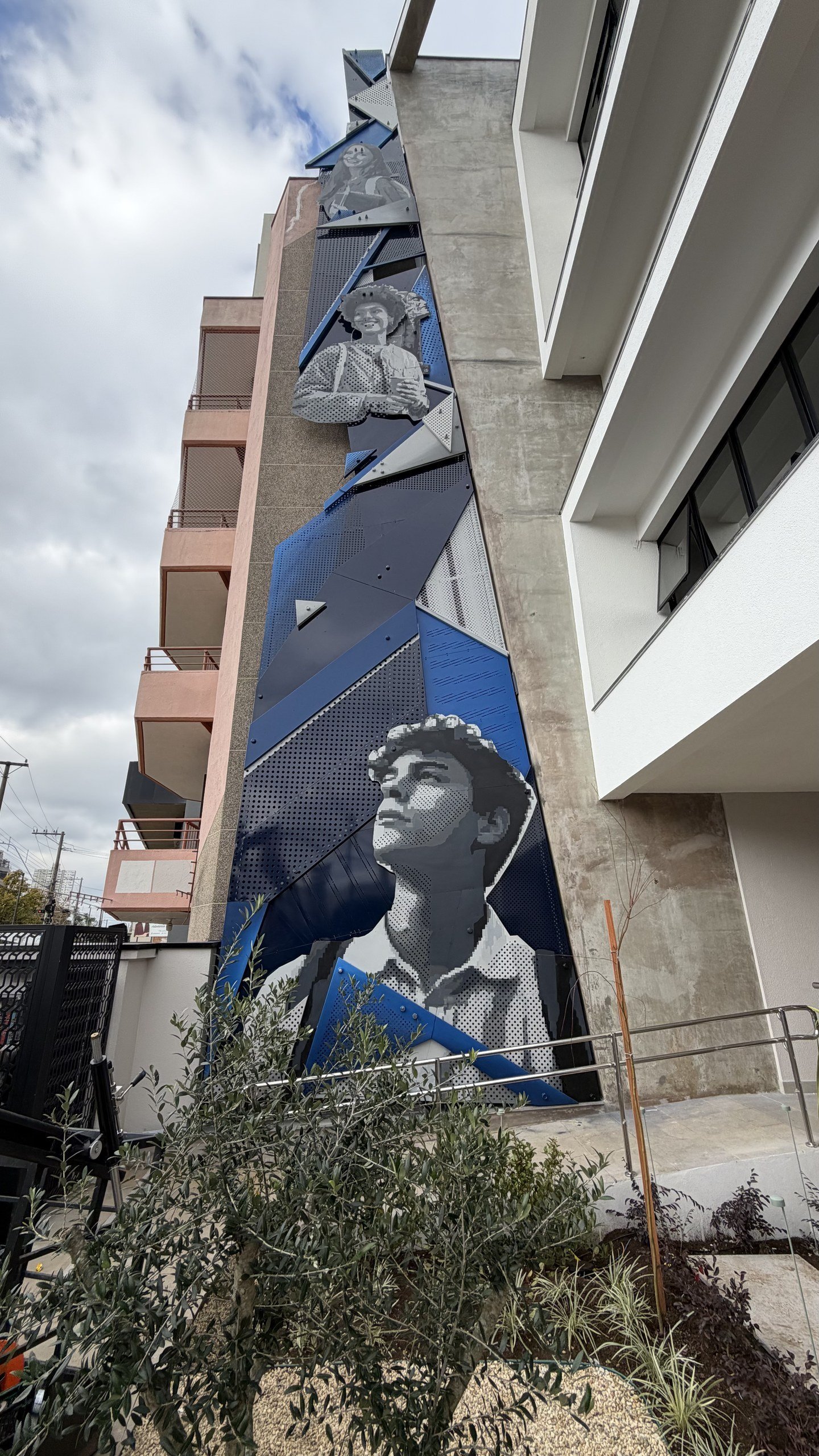 A escultura de chapas recortadas subindo a fachada do prédio do CIEE, com o rosto de um jovem