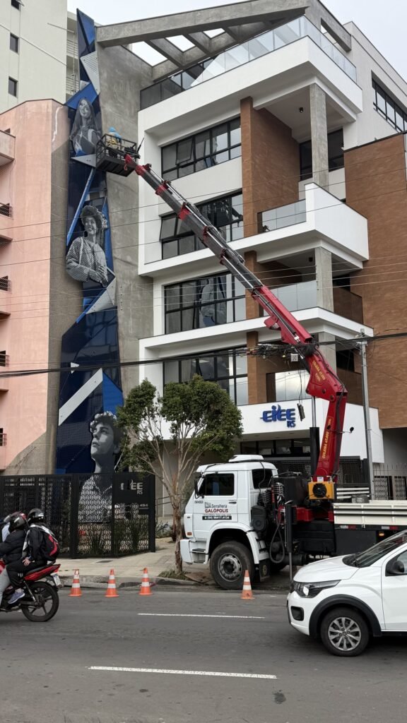 Caminhão com guindaste instalando as peças na fachada, vista da rua
