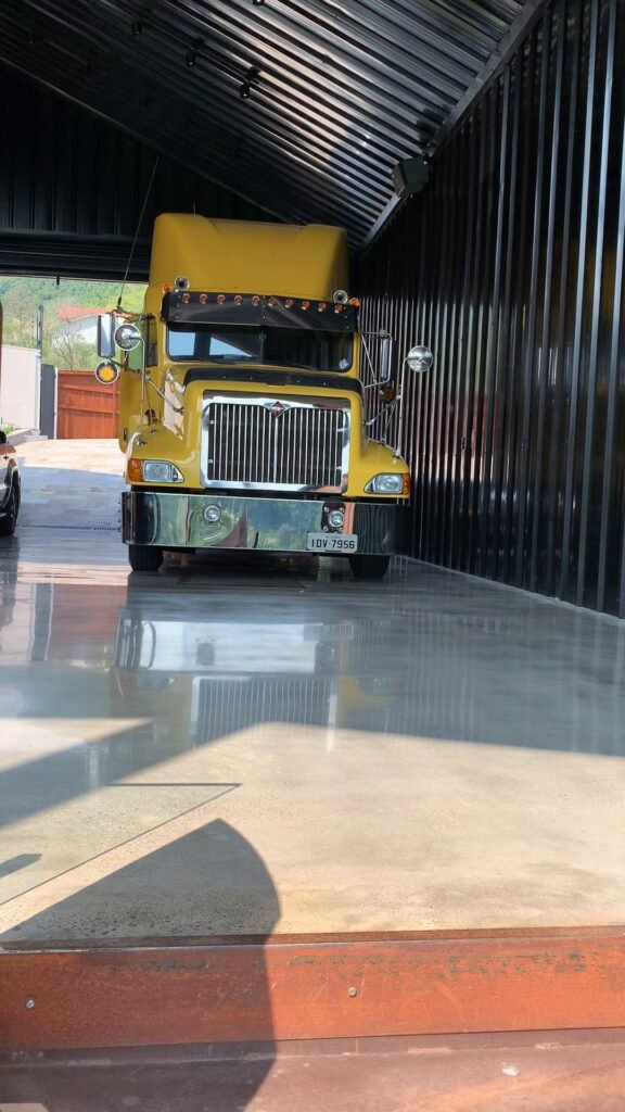 Caminhão amarelo estacionado dentro do galpão de paredes pretas