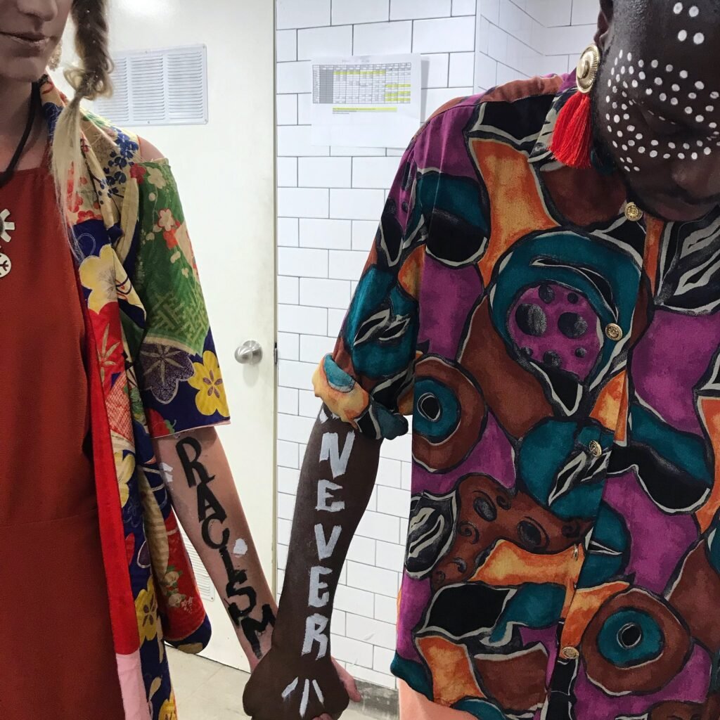 Braço com a frase Racism Never escrita e camisa pintada à mão
