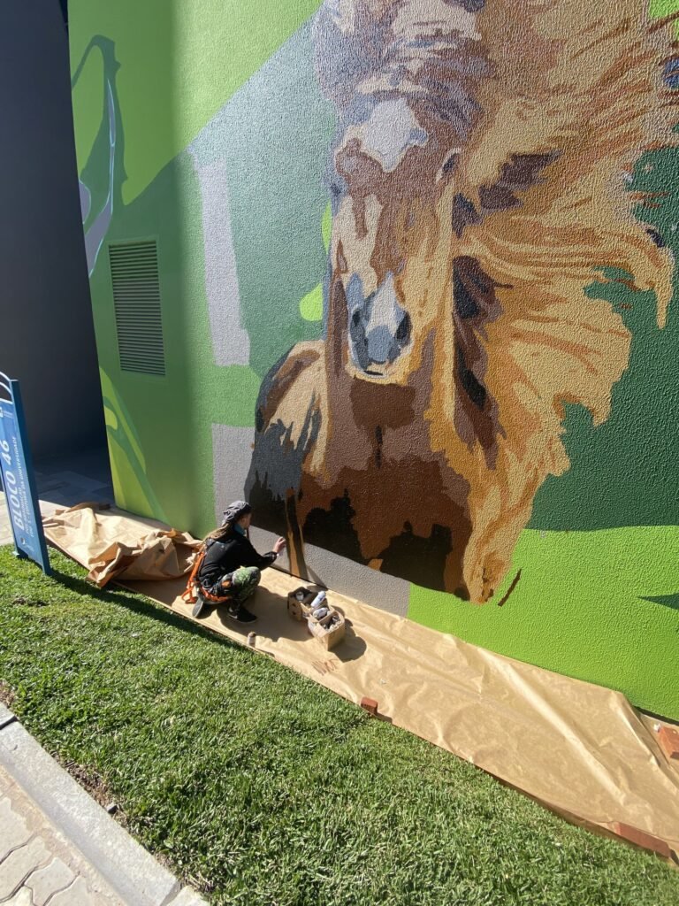 Detalhe do cavalo pintado na base da fachada, com o papel de proteção no gramado