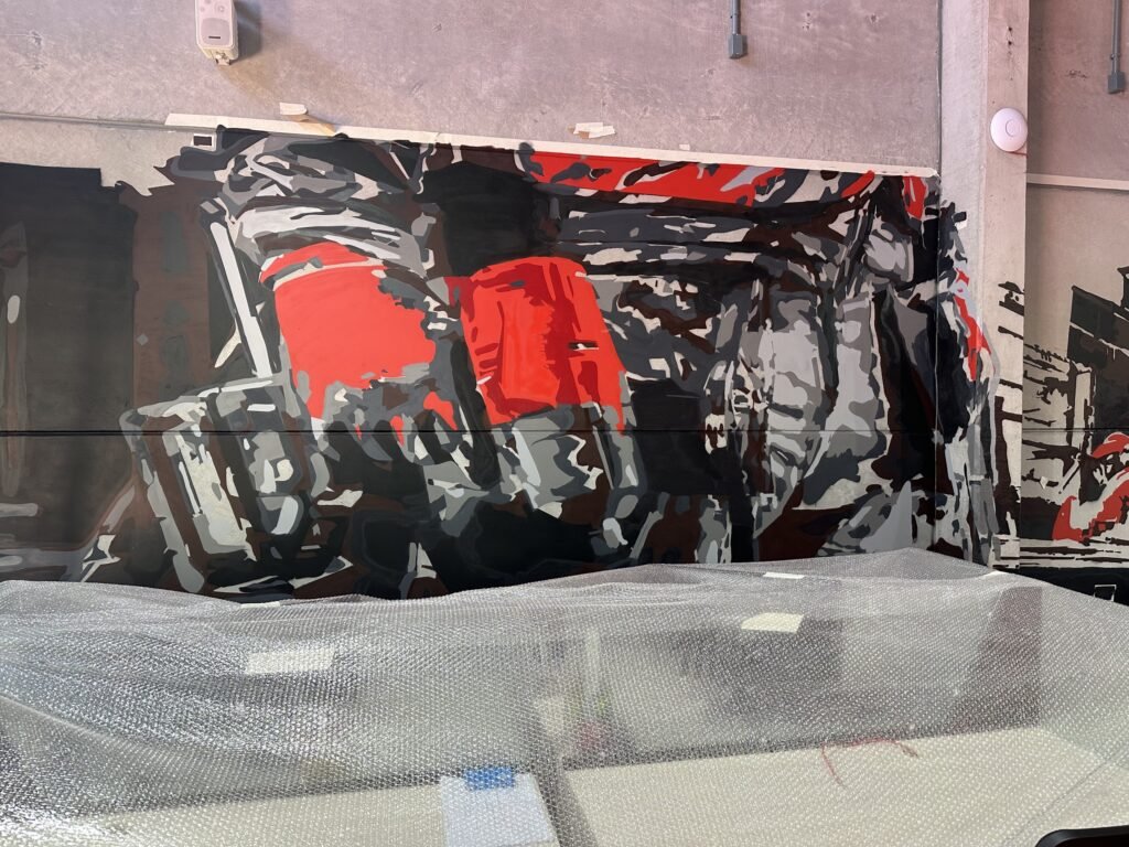 Detalhe do mural com ferramentas vermelhas da Milwaukee entre formas pretas e cinza