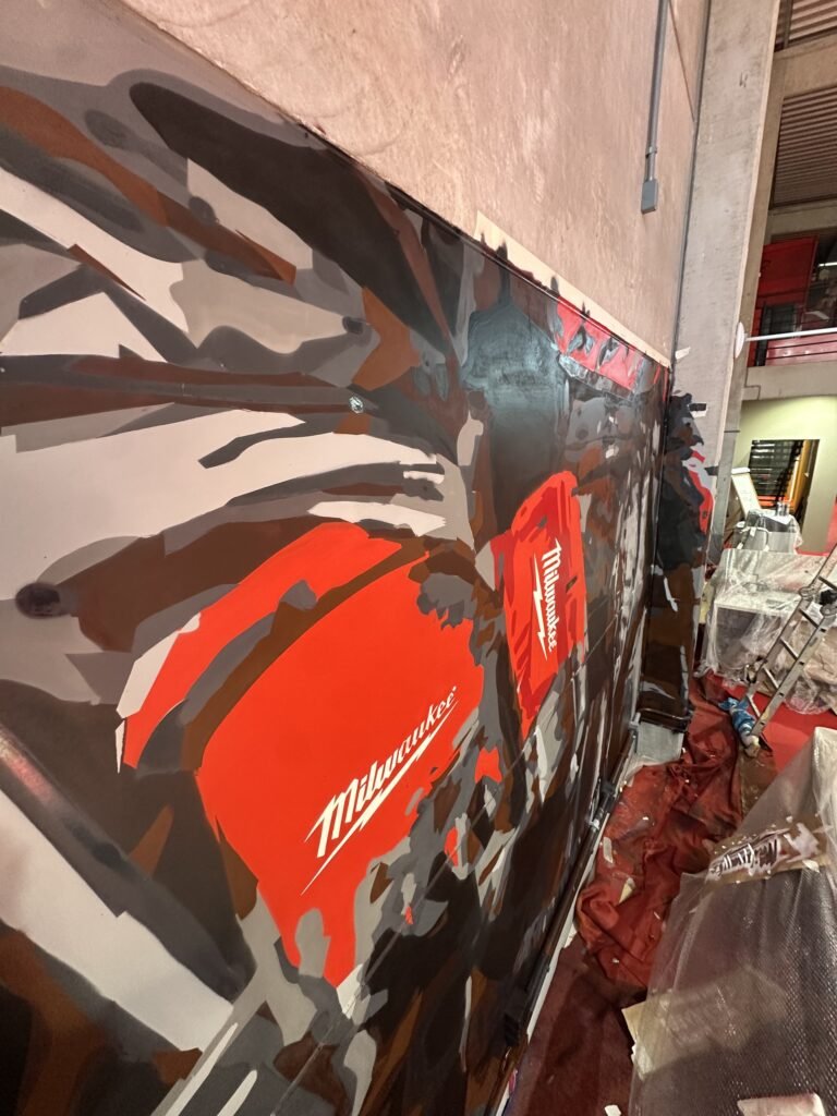 Ferramenta vermelha com o logotipo da Milwaukee pintada em primeiro plano no mural