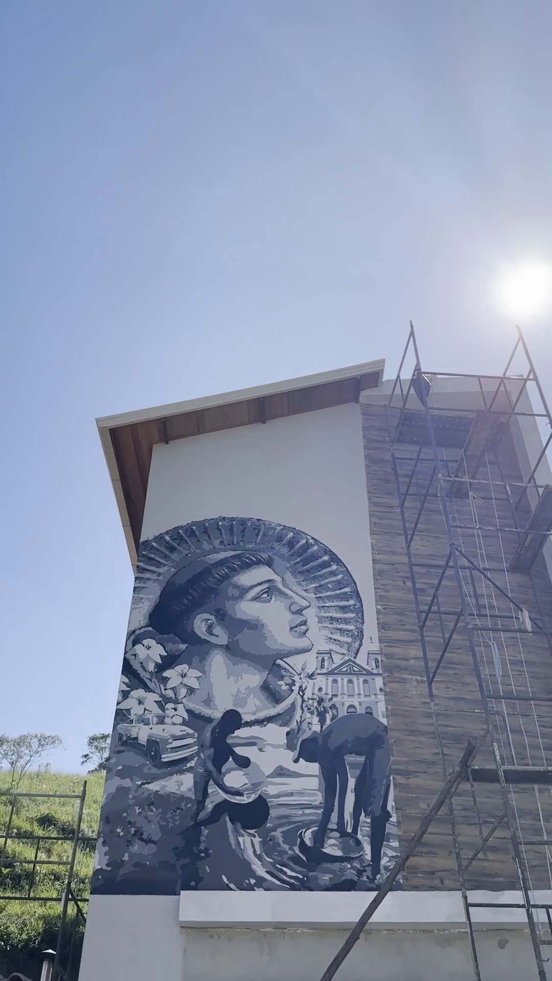 Fachada alta e estreita com um rosto em preto e branco pintado, e o andaime ao lado