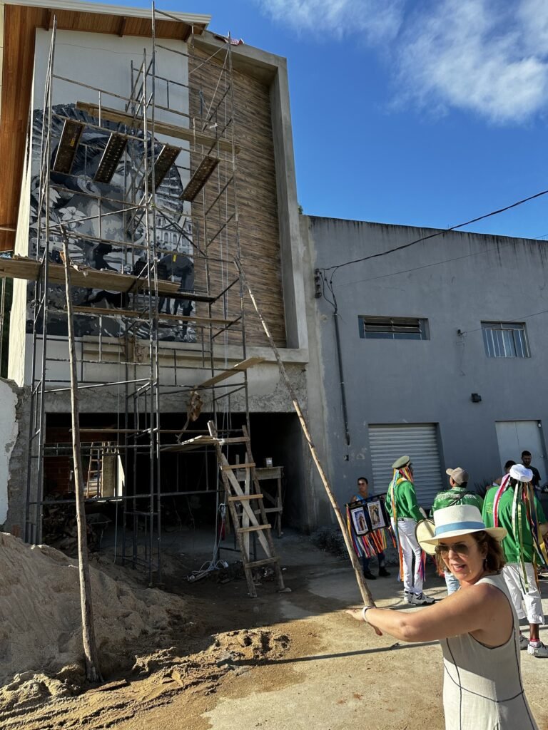 O prédio com o andaime montado e pessoas de verde e branco na rua