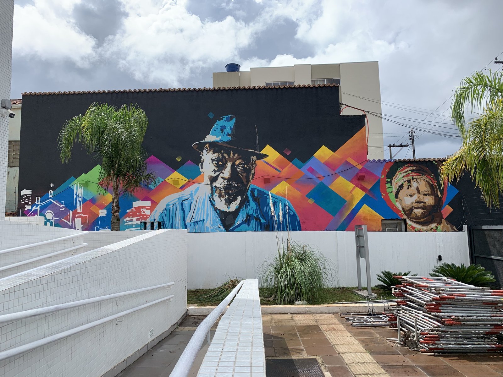 O paredão do Ministério Público Federal pintado de ponta a ponta, com os dois retratos no meio da geometria colorida