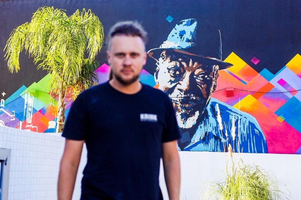 Gustavo Gomes em frente ao retrato do homem de chapéu