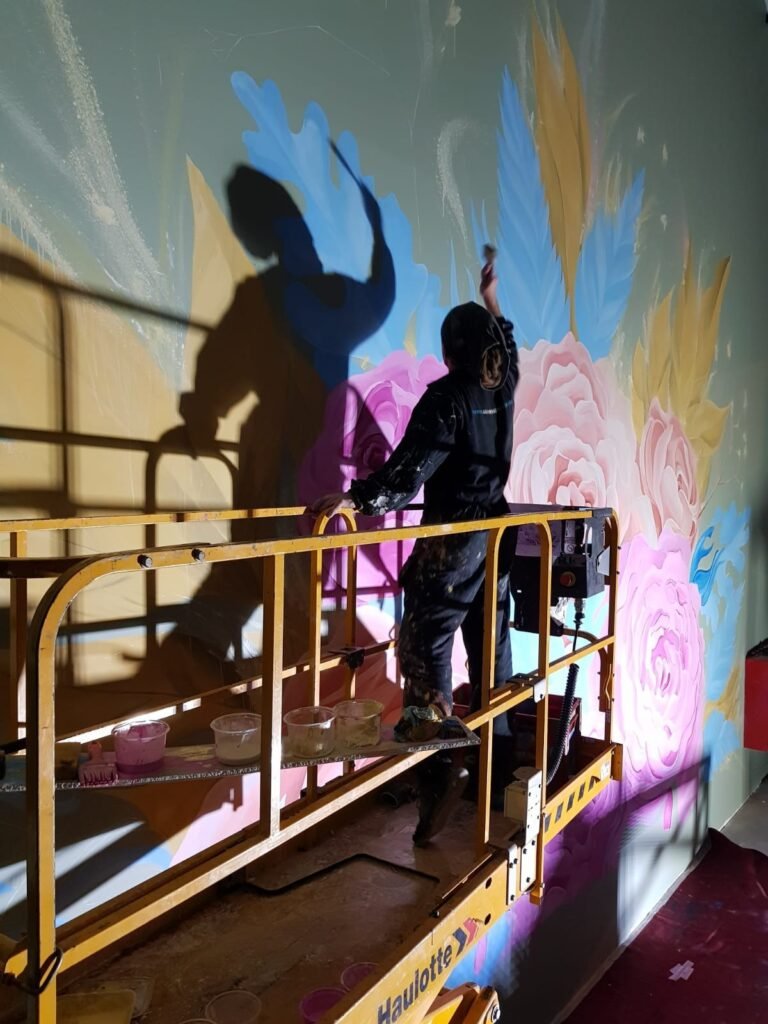 Pintor na plataforma, com a própria sombra projetada sobre as flores