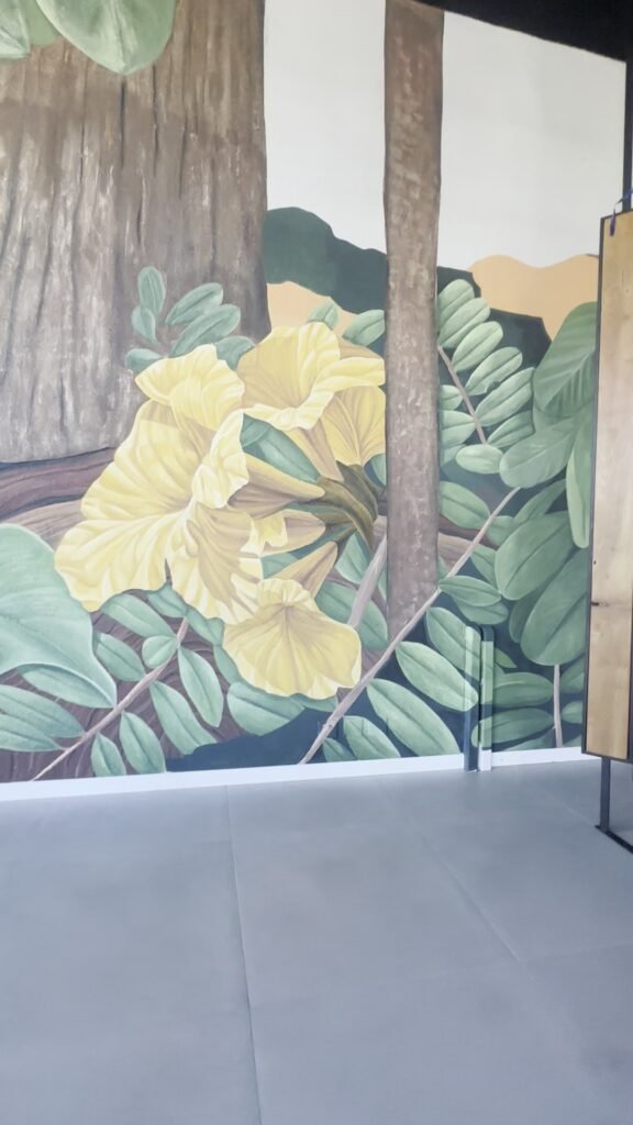 O mural visto do fundo do espaço, com as janelas e o piso de concreto