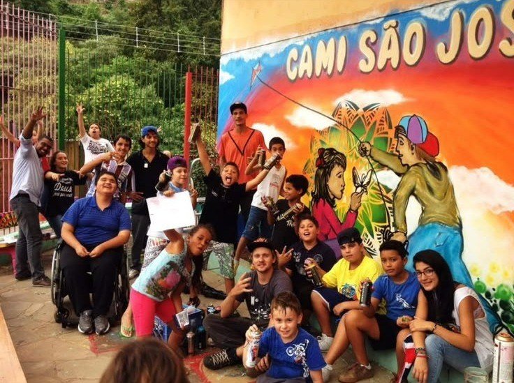 Turma reunida diante do mural colorido pintado no CAMI São José