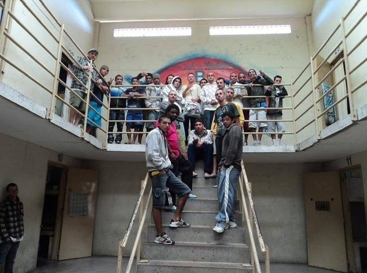 Grupo do movimento hip hop de Caxias reunido numa escadaria, com um graffiti ao fundo