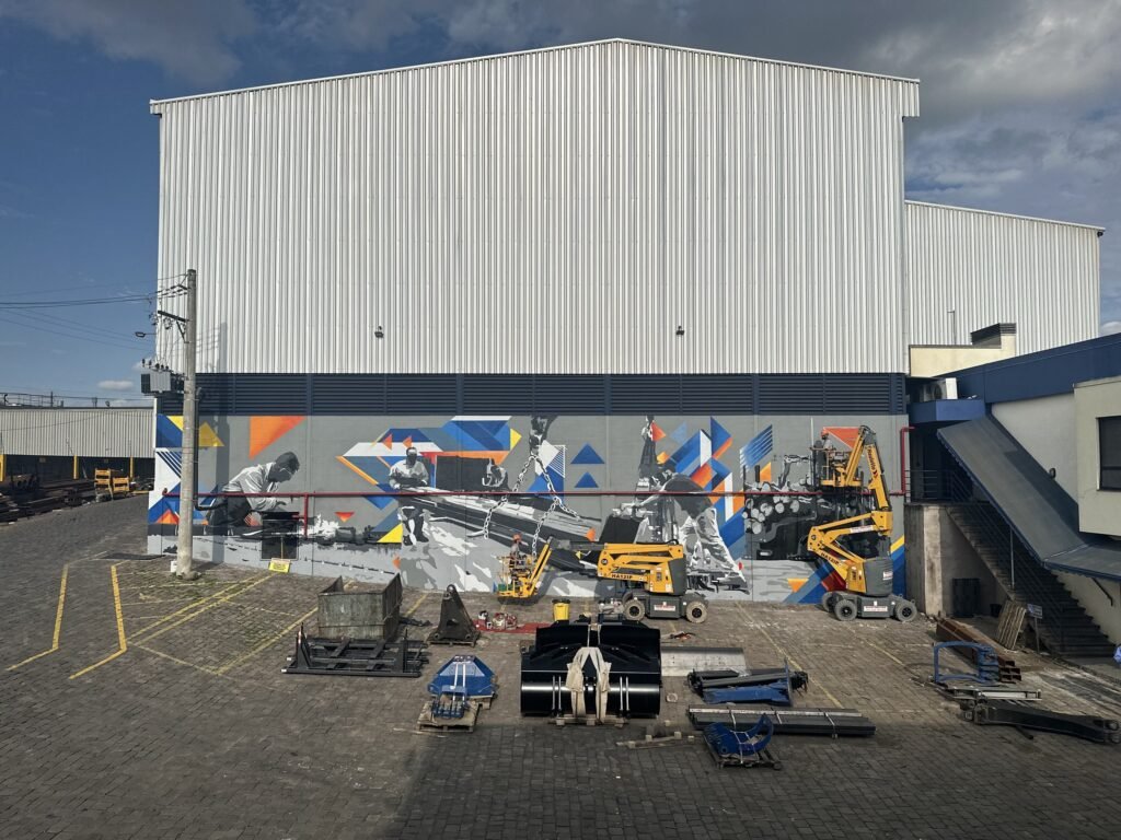 Galpão industrial com a faixa geométrica pintada e as plataformas ainda em frente