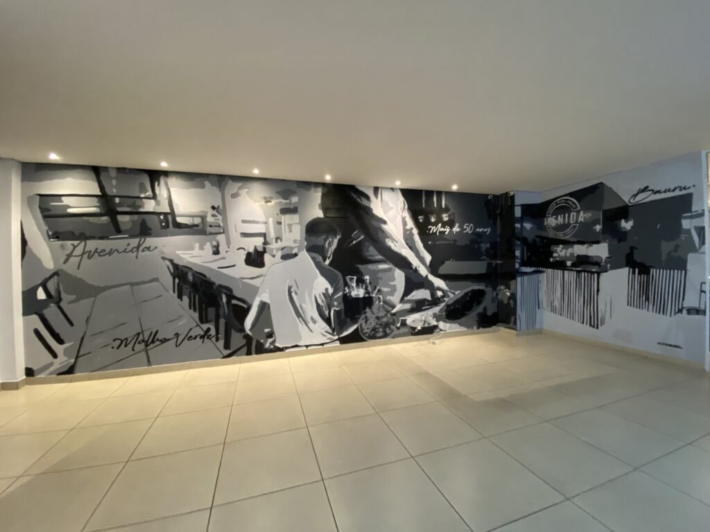 Mural em preto e branco com uma cena de cozinha ocupando a parede do salão