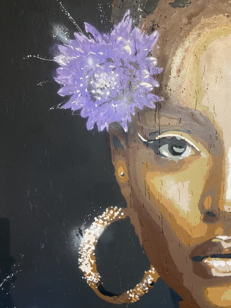 Retrato de mulher com uma flor roxa no cabelo e argola dourada