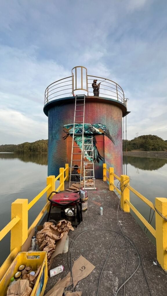 Pintor no alto da torre da represa, com a água em volta