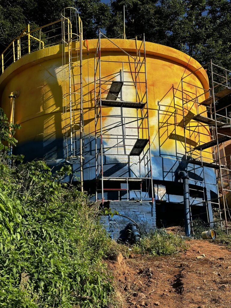 Reservatório amarelo e azul cercado de andaime durante a pintura