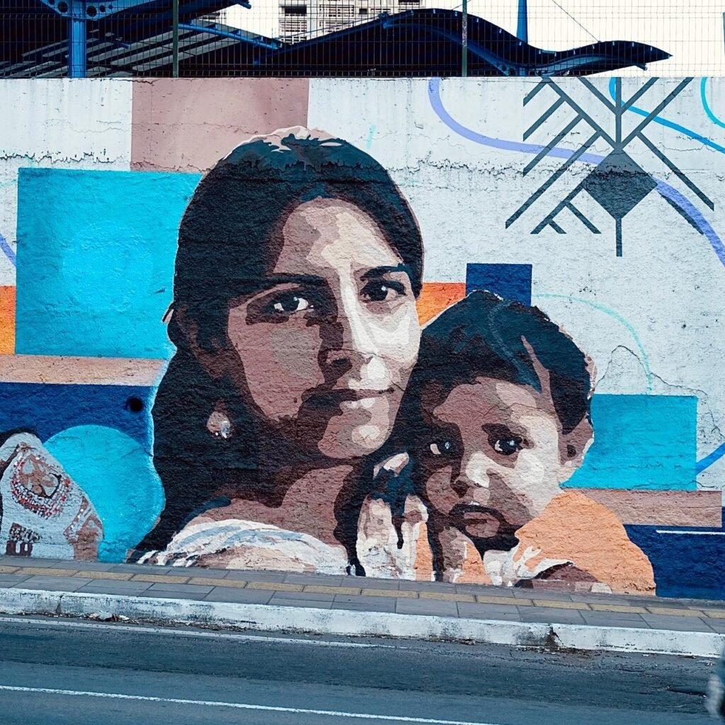 Retrato de uma mulher com uma criança no colo, sobre planos azuis e laranja