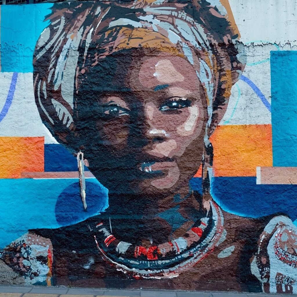 Retrato de uma mulher negra de turbante e colares, sobre fundo azul