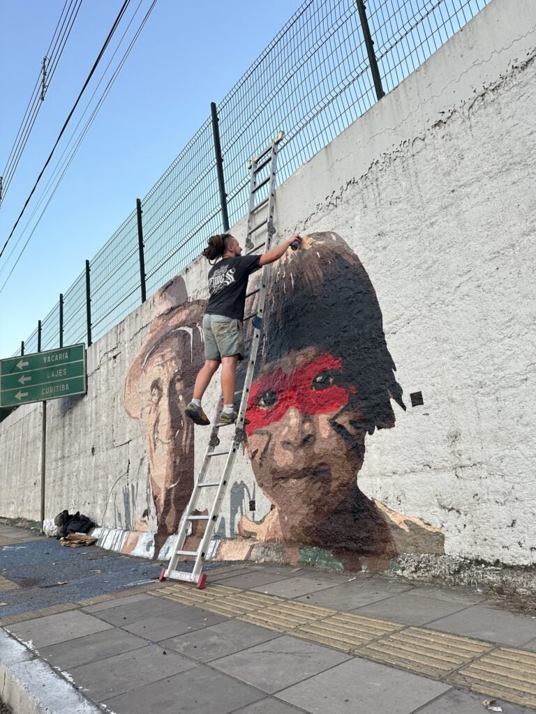 Pintor numa escada encostada no muro, começando os primeiros retratos