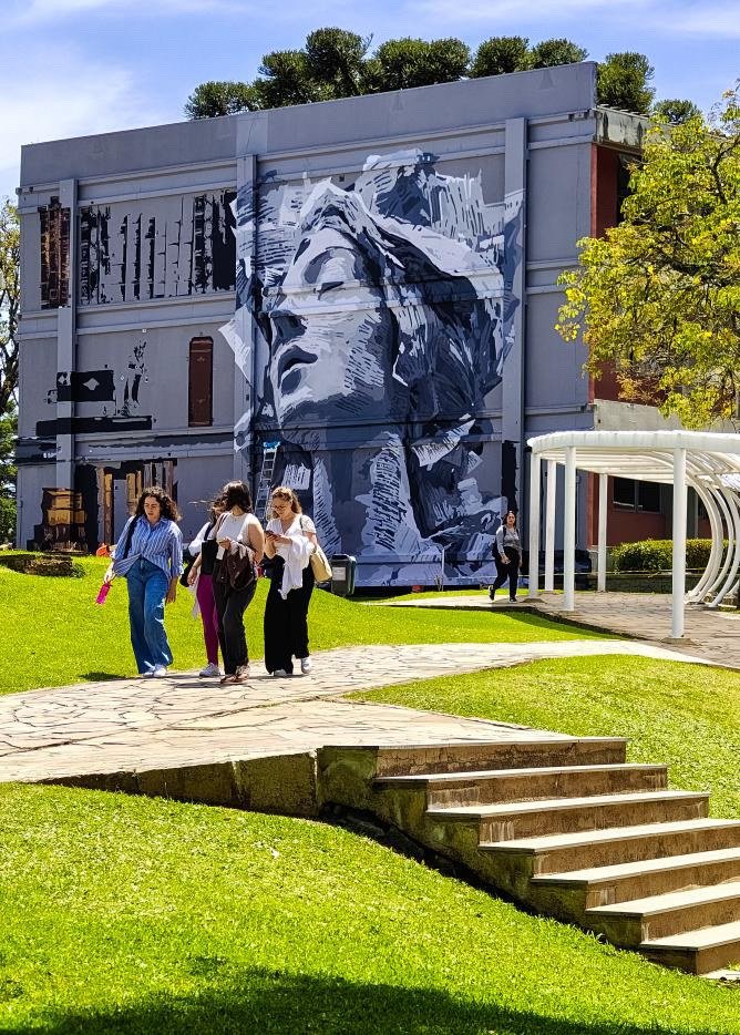 Pessoas passando pelo gramado em frente ao mural