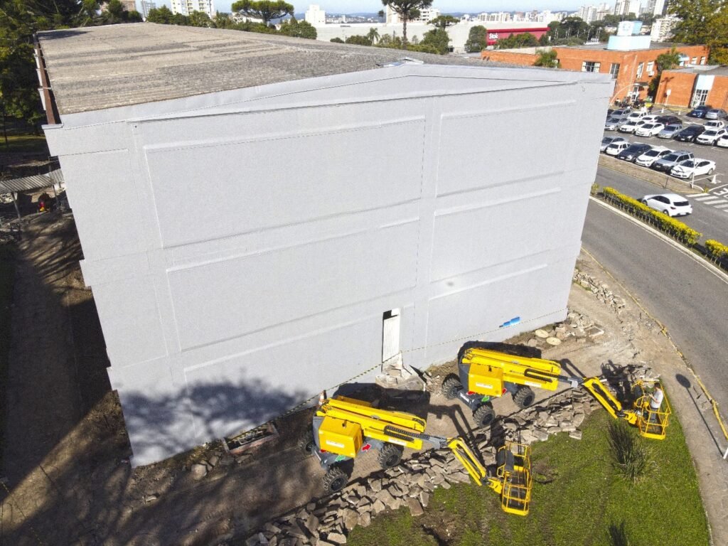 A fachada do Bloco H ainda branca, com as plataformas chegando, vista de drone